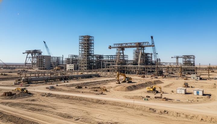 Закупки в нефтегазе: как бюрократия съедает прибыль и тормозит проекты Масштабная строительная площадка нефтегазового проекта с недостроенными трубопроводами и простаивающей техникой.