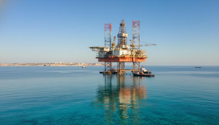 Морская нефтегазовая разведочная платформа в Средиземном море на фоне удаленного побережья Мальты.